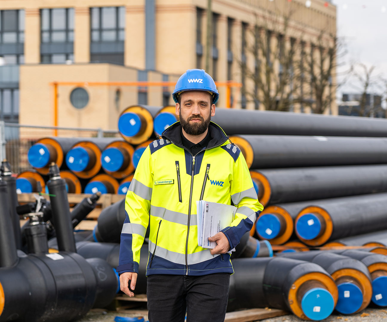 WWZ-Mitarbeiter steht vor Rohrleitungen für den Wärmeverbund Ennetsee. 
