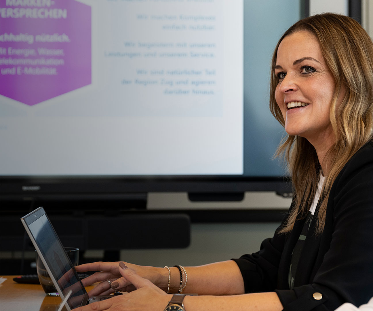 Frau und Mann sitzen in Besprechung und lachen. 