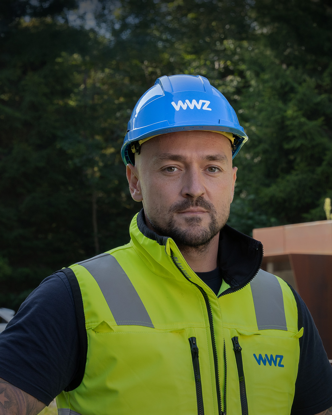 Mitarbeiter mit Helm und Leuchtweste blicken in Kamera.