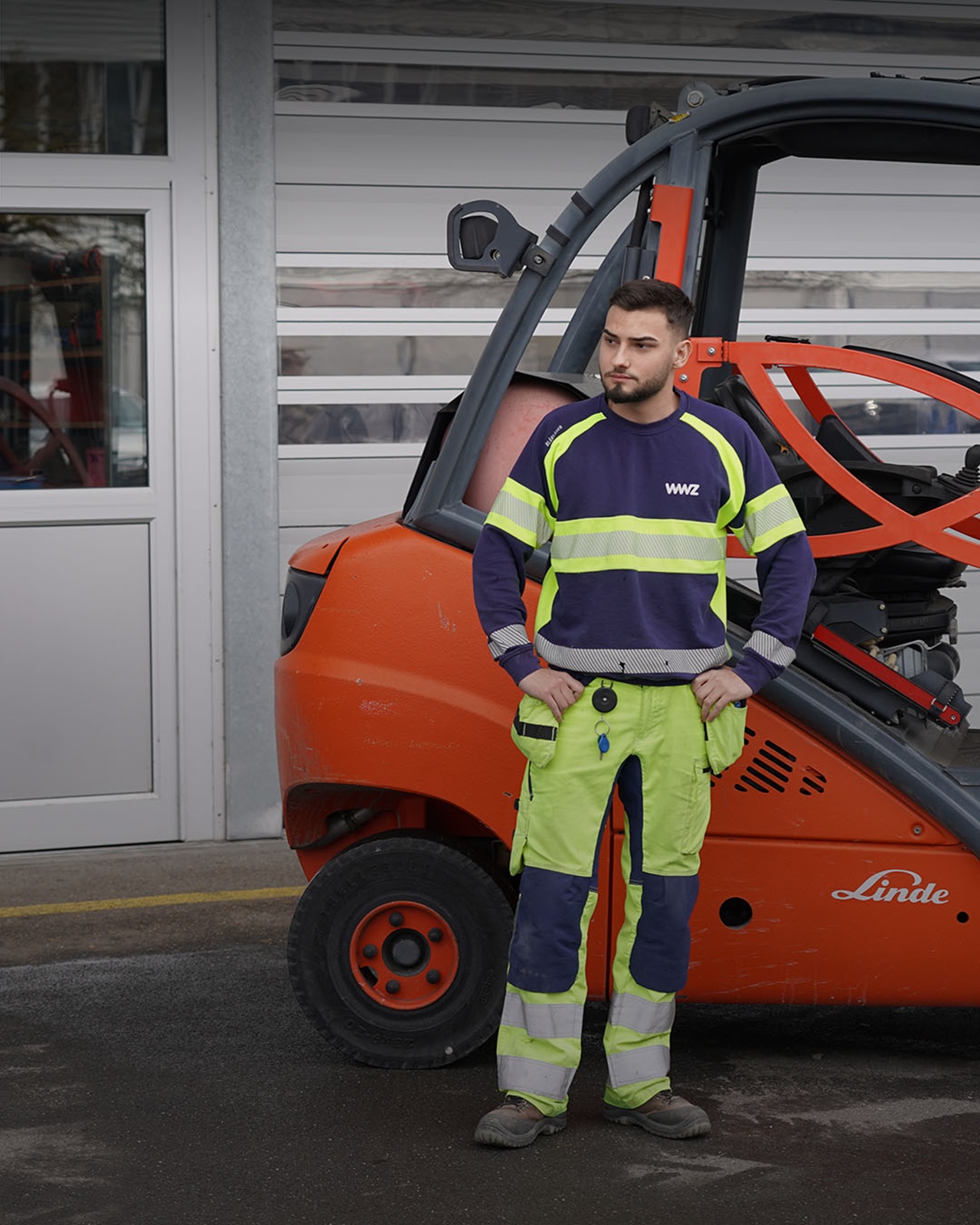 Logistiker in WWZ-Arbeitskleidung steht vor Gabelstapler