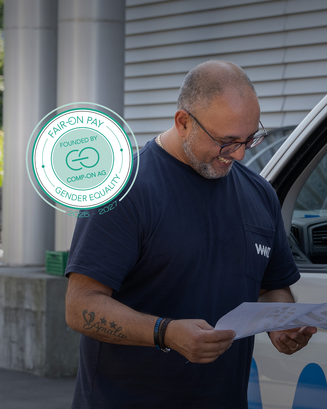 Mann steht vor WWZ-Auto und schaut sich einen Plan an. 