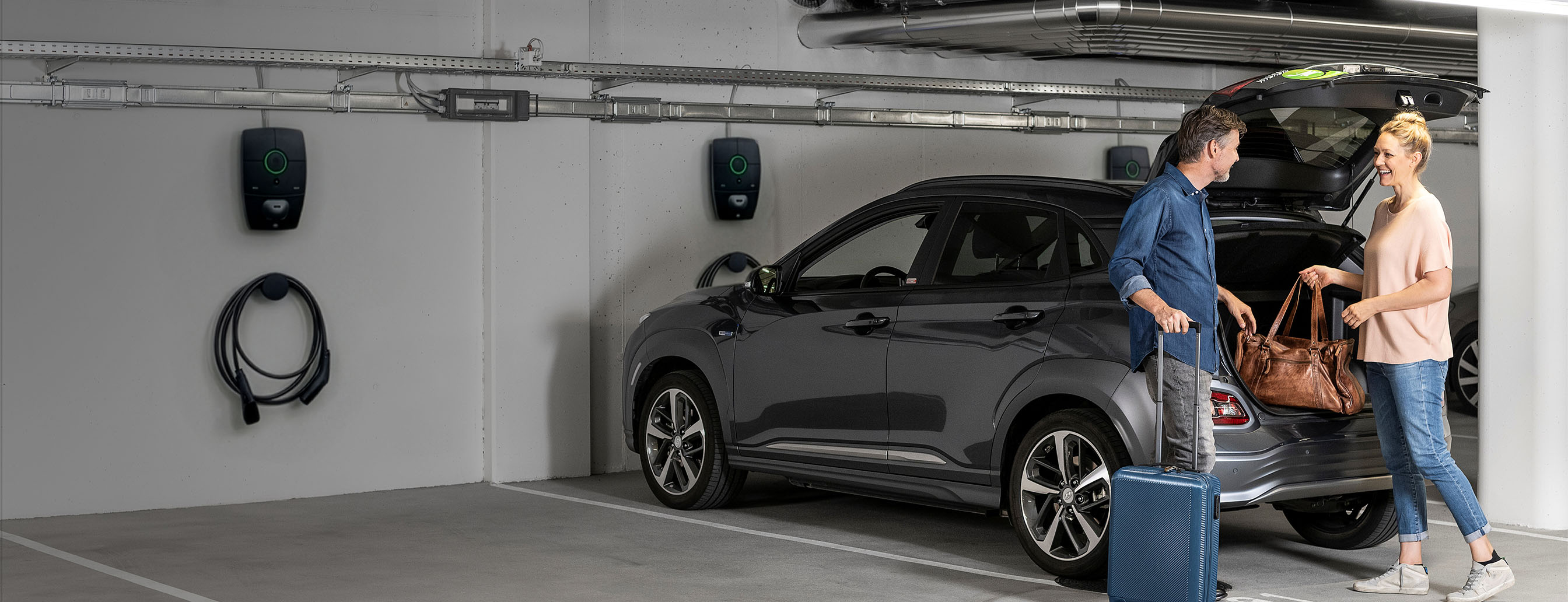Frau und Mann vor Elektroauto und Ladestation