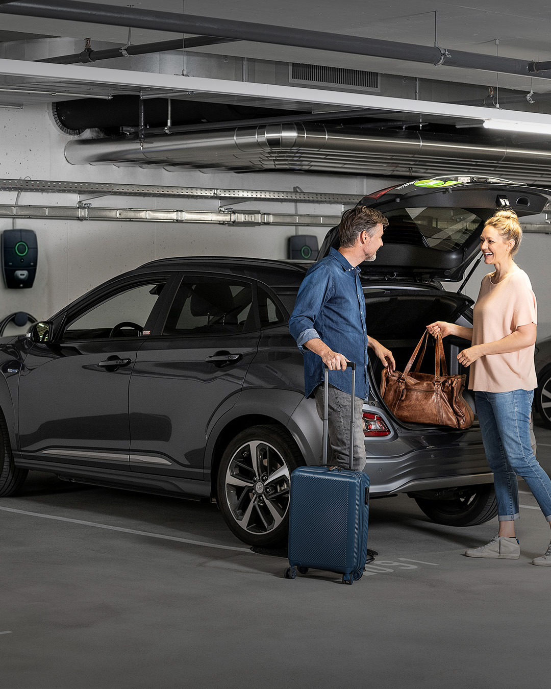 Frau und Mann vor Elektroauto und Ladestation