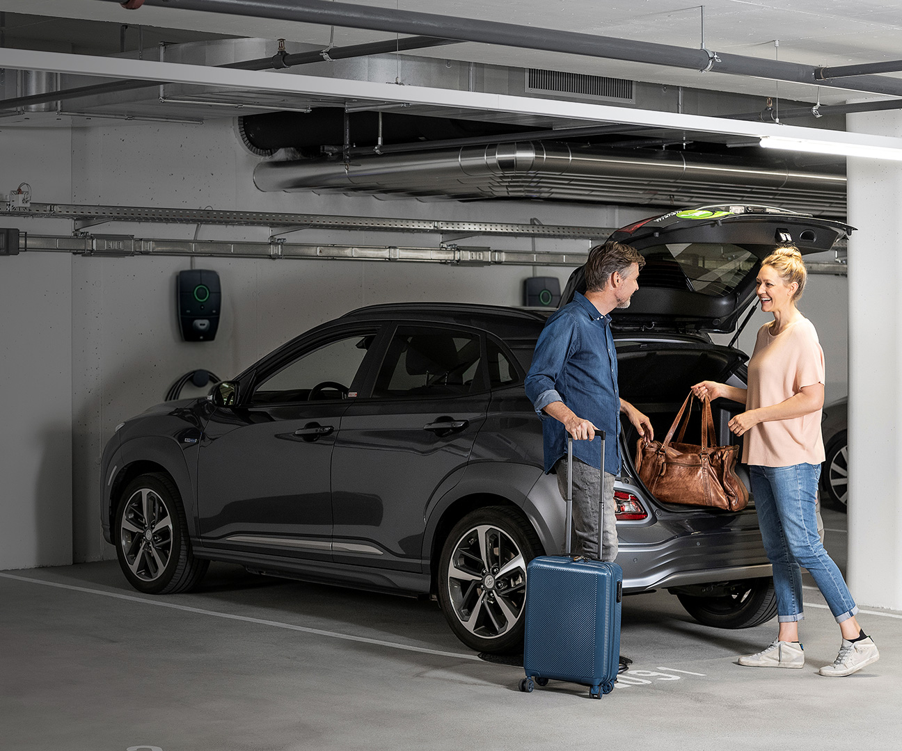 Frau und Mann vor Elektroauto und Ladestation