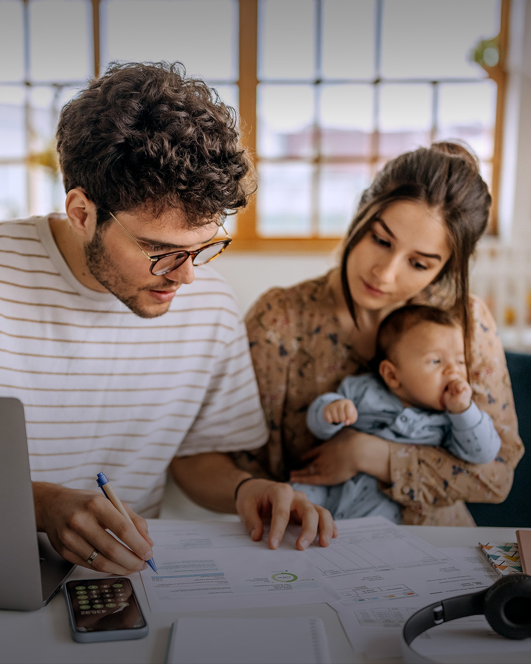 Junge Familie rechnet zusammen an Esstisch.
