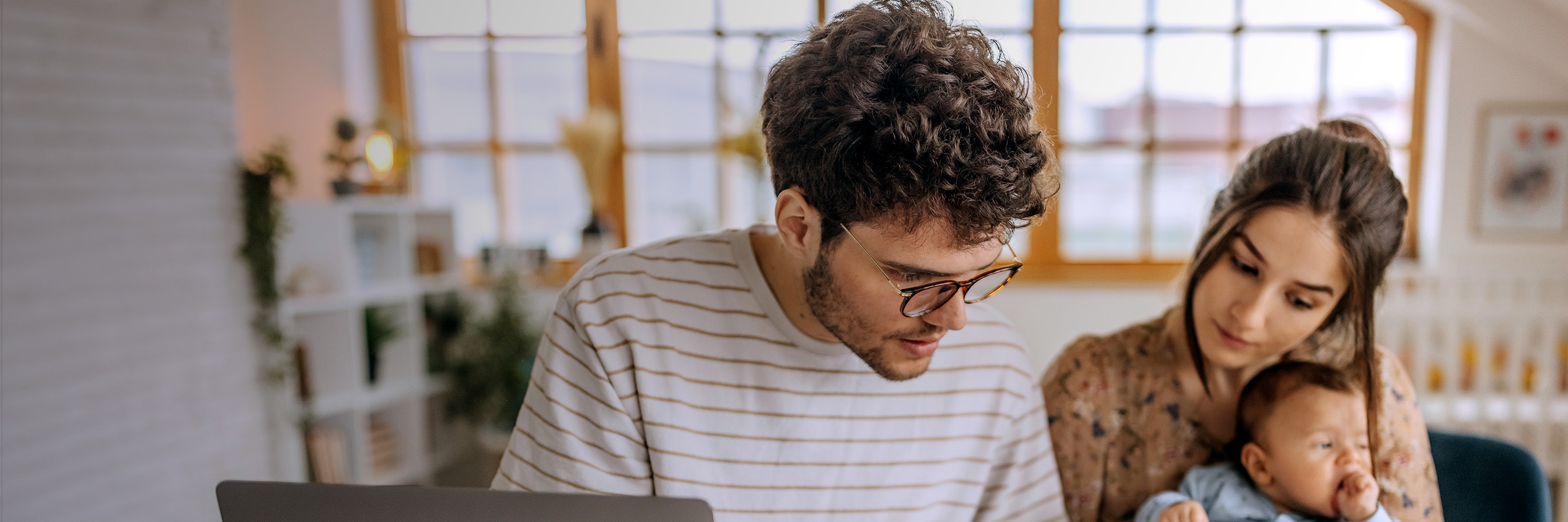 Junge Familie rechnet zusammen an Esstisch.