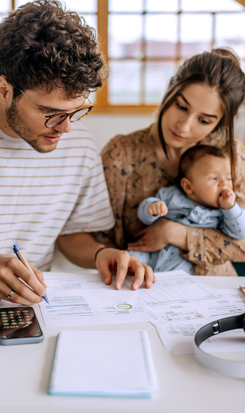 Junge Familie rechnet zusammen an Esstisch.