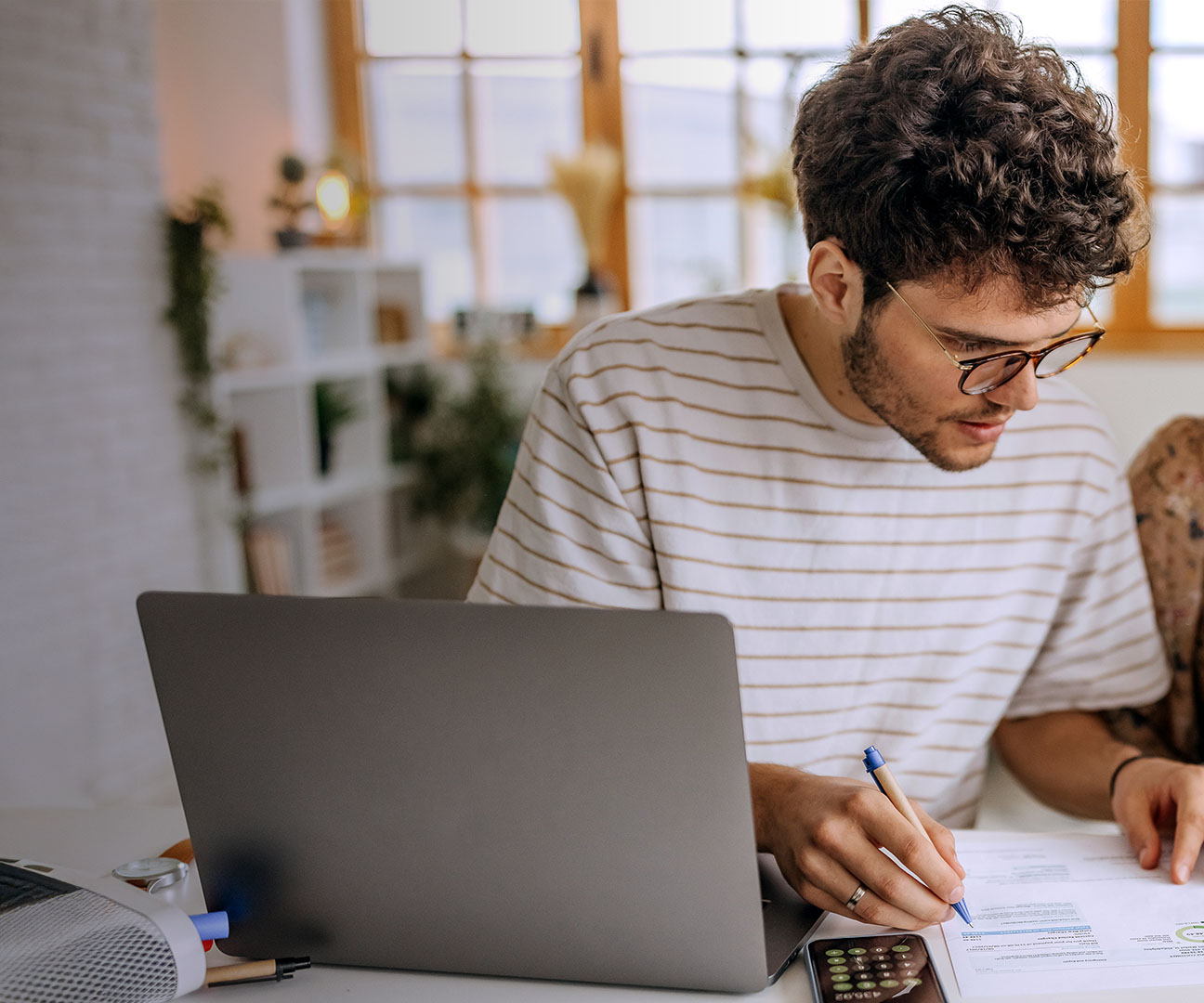 Junge Familie rechnet zusammen an Esstisch.