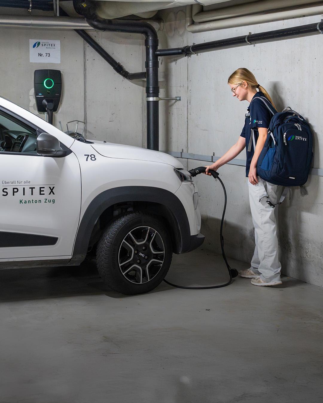 Pflegefachfrau schliesst E-Auto an Ladestation an