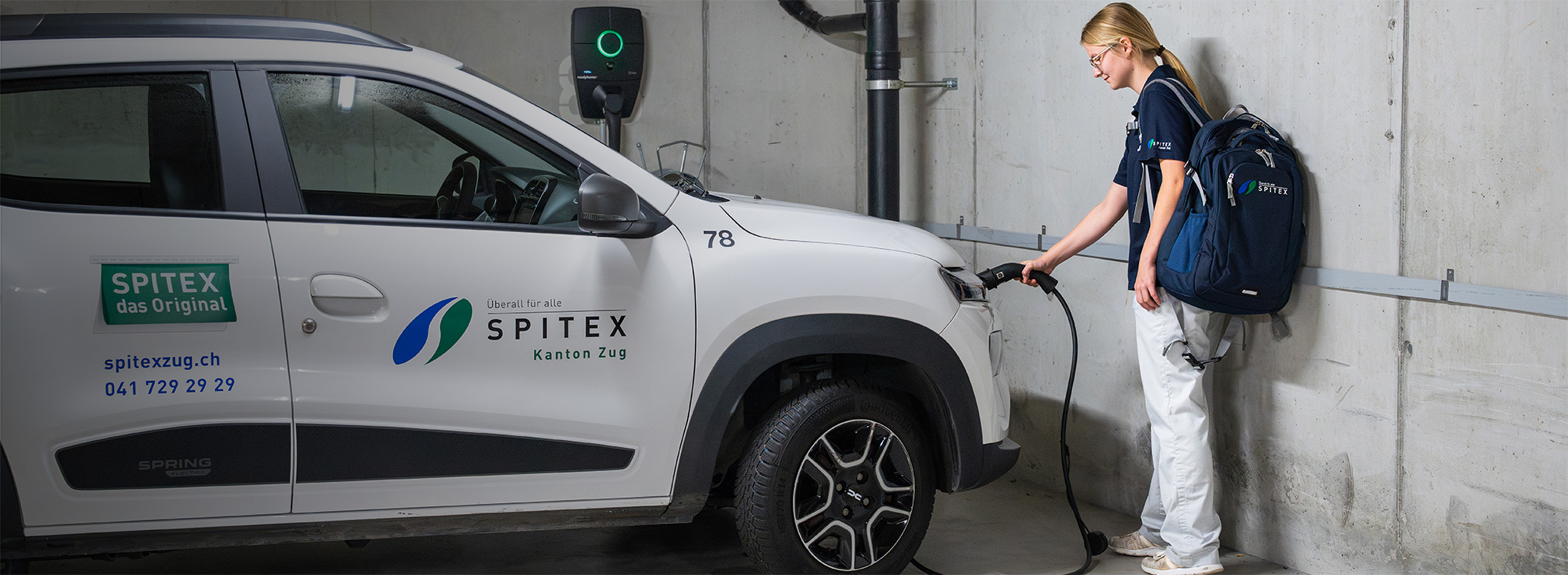 Pflegefachfrau schliesst E-Auto an Ladestation an