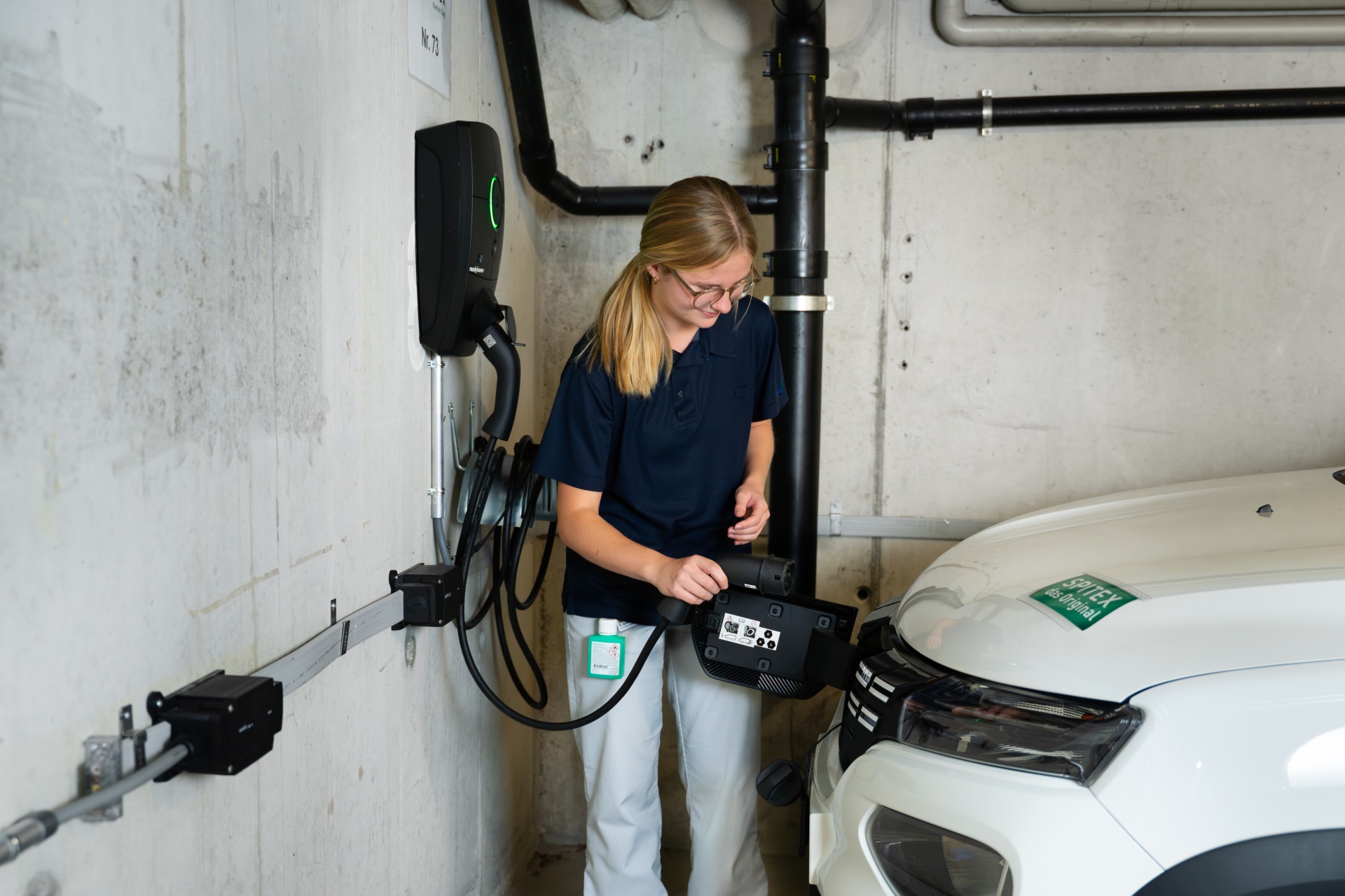 Pflegefachfrau lädt Elektroauto in Tiefgarage