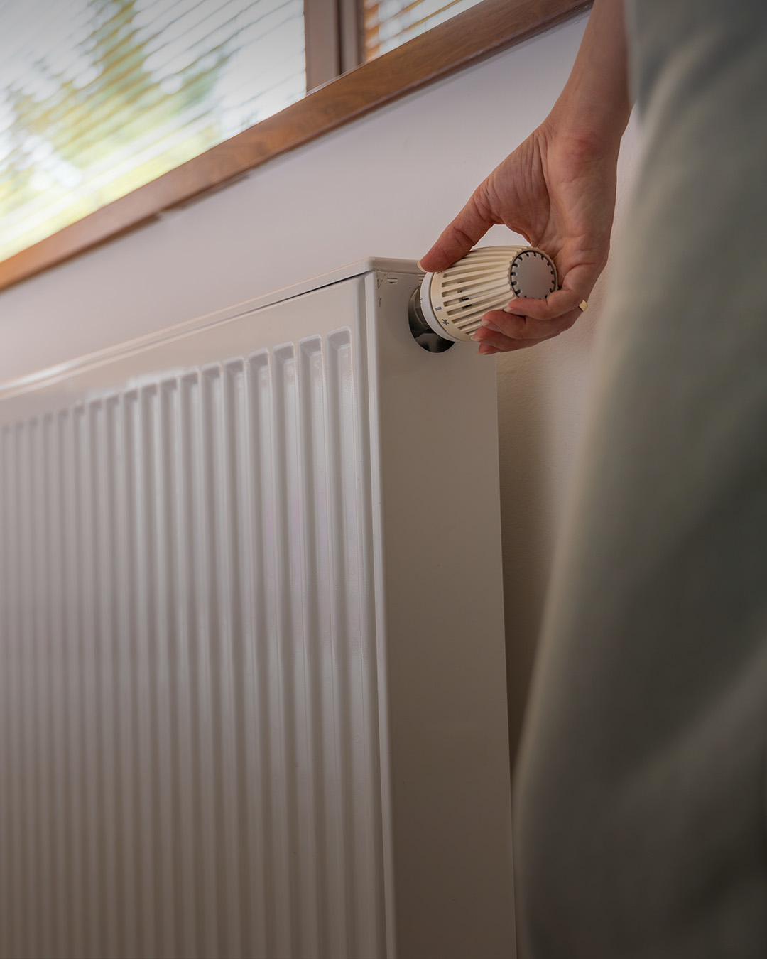 Frau dreht an Heizung