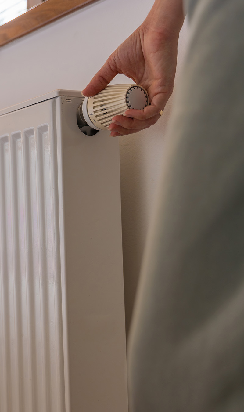 Frau dreht an Heizung