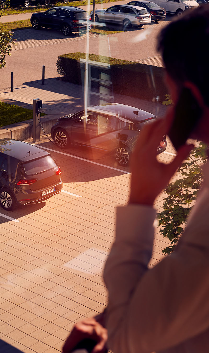 Mann blickt aus Fenster auf E-Autos